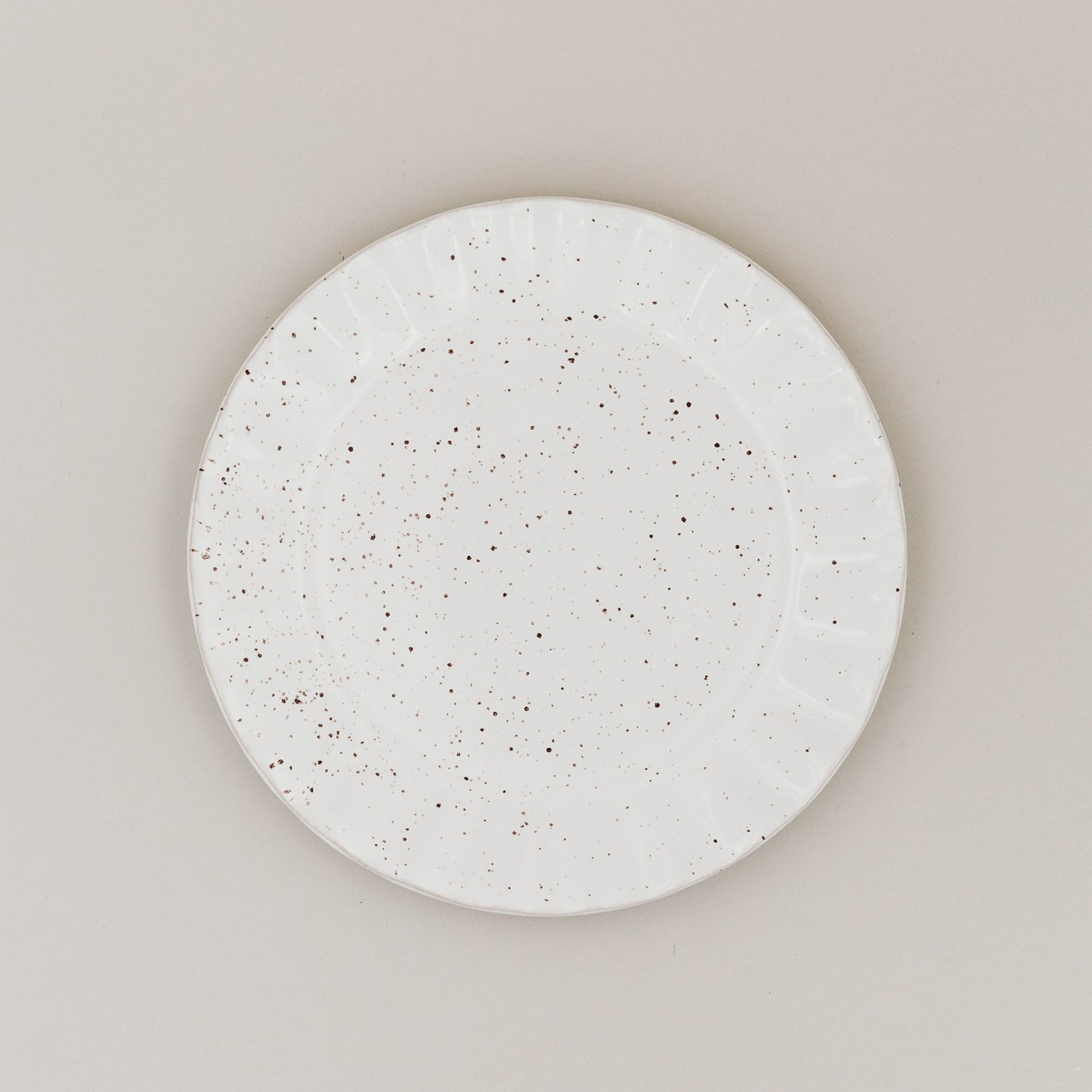 Speiseteller Colina von oben mit gesprenkelter Glasur und welligem Rand auf hellem Untergrund