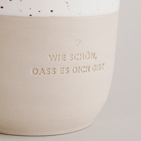 Nachaufnahme von der Prägung "Wie schön, dass es dich gibt" auf einem Steingut Becher.