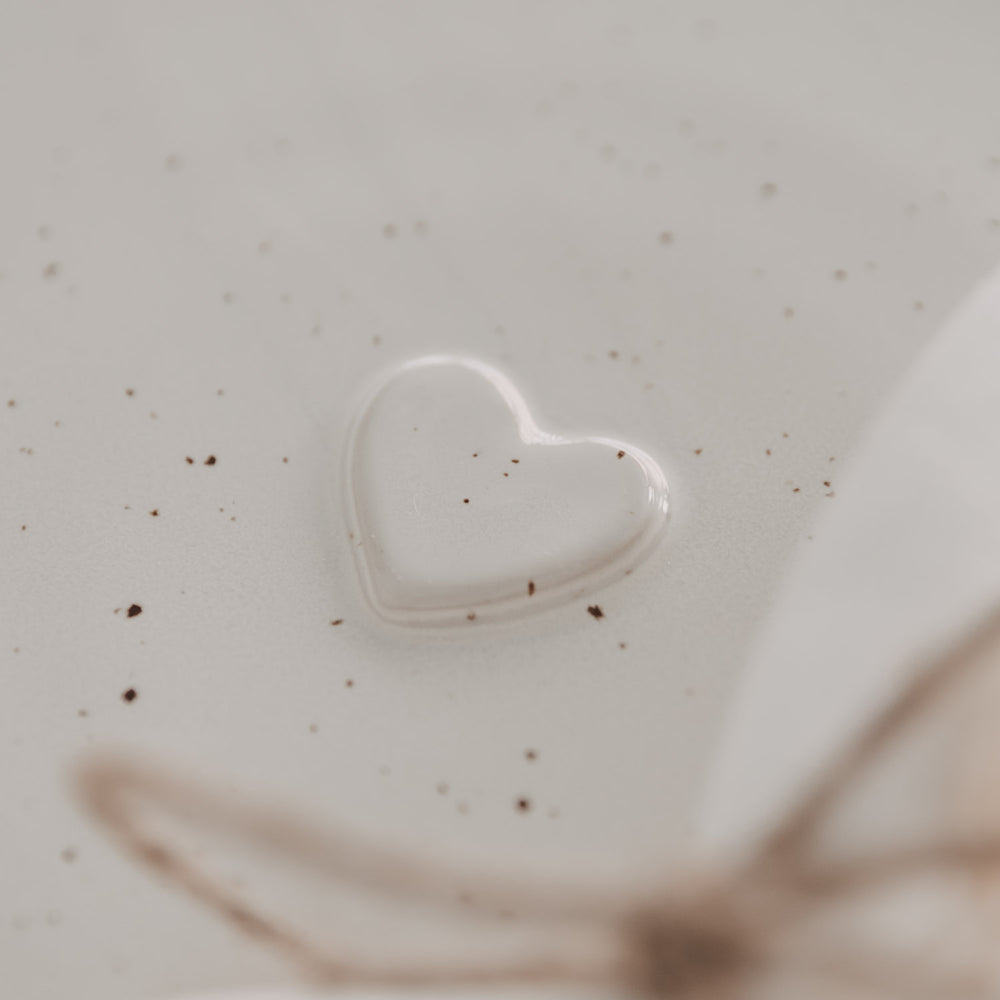 Detailaufnahme des eingeprägten Herzmotivs auf dem Frühstücksteller Calma aus gesprenkelter Keramik.