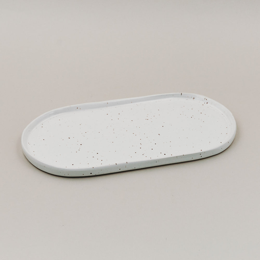 Servierplatte Calma klein aus weißem Steingut mit Sprenkelmuster auf hellem Untergrund