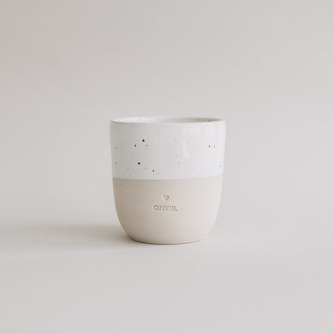 Keramikbecher „Onkel“ in Beige und Weiß mit gesprenkelter Glasur und Herzprägung, freistehend vor hellem Hintergrund.