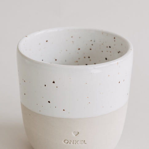 Nahaufnahme des Keramikbechers „Onkel“ mit weißer, gesprenkelter Glasur und matter beiger Unterseite.