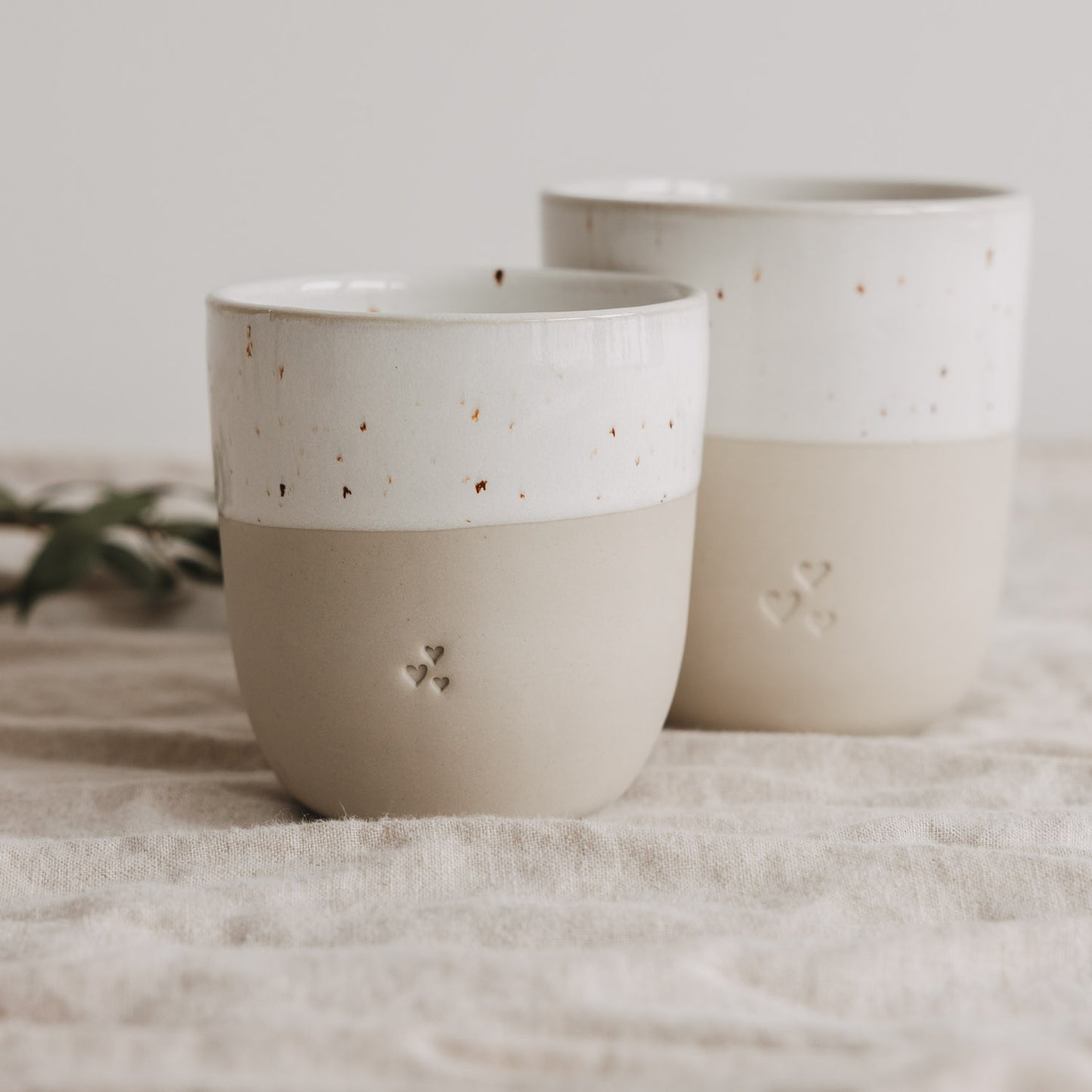 Zwei Keramik Mini Becher mit Herzprägung in Beige Weiß, handgefertigter Look auf Leinentuch