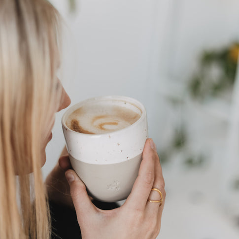 Person trinkt Kaffee aus Keramikbecher mit Sternen, stilvoller Alltagsbecher