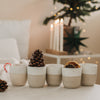 Keramikbecher Set mit Weihnachtsprägung, Zuckerstange, Orange und Tannenzapfen, festlich dekoriert