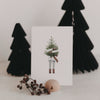 Kartenständer Halbrund Tanne mit Postkarte und Deko vor schwarzen Papierbäumen