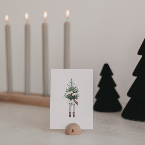 Postkarte im Halbrund-Kartenständer vor Kerzenleuchter und schwarzer Weihnachtsdeko