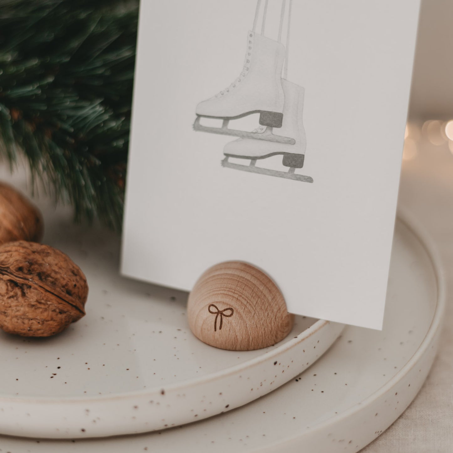 Kartenhalter halbrund aus Holz mit Schleifenmotiv, festlich dekoriert auf gesprenkeltem Teller mit Karte