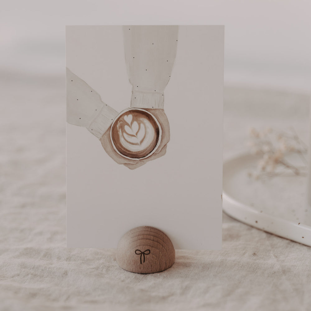 Kartenständer aus Holz in Halbrundform mit Schleife, hält Karte mit Latte Art auf Leinentisch