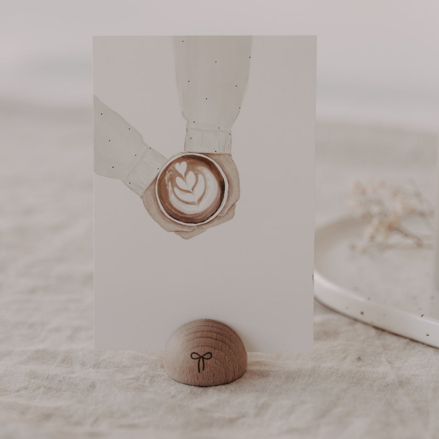 Kartenständer aus Holz in Halbrundform mit Schleife, hält Karte mit Latte Art auf Leinentisch