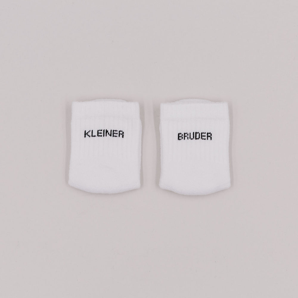 Weiße Babysocken mit Schriftzug „Kleiner Bruder“ auf neutralem Hintergrund