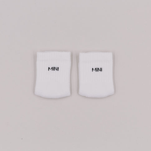 Weiße Babysocken mit schwarzer „MINI“-Stickerei auf hellem Untergrund, flach nebeneinandergelegt