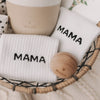 Detailaufnahme: Socken mit Mama-Schriftzug in einem Geschenkkorb mit Keramikbecher und Holzaccessoires.