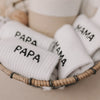 Socken mit „PAPA“-Aufschrift im Geschenkkorb mit weiteren Mama- und Papa-Socken.