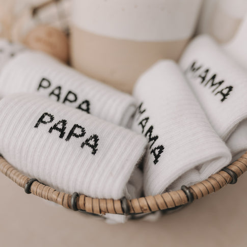 Socken mit „PAPA“-Aufschrift im Geschenkkorb mit weiteren Mama- und Papa-Socken.