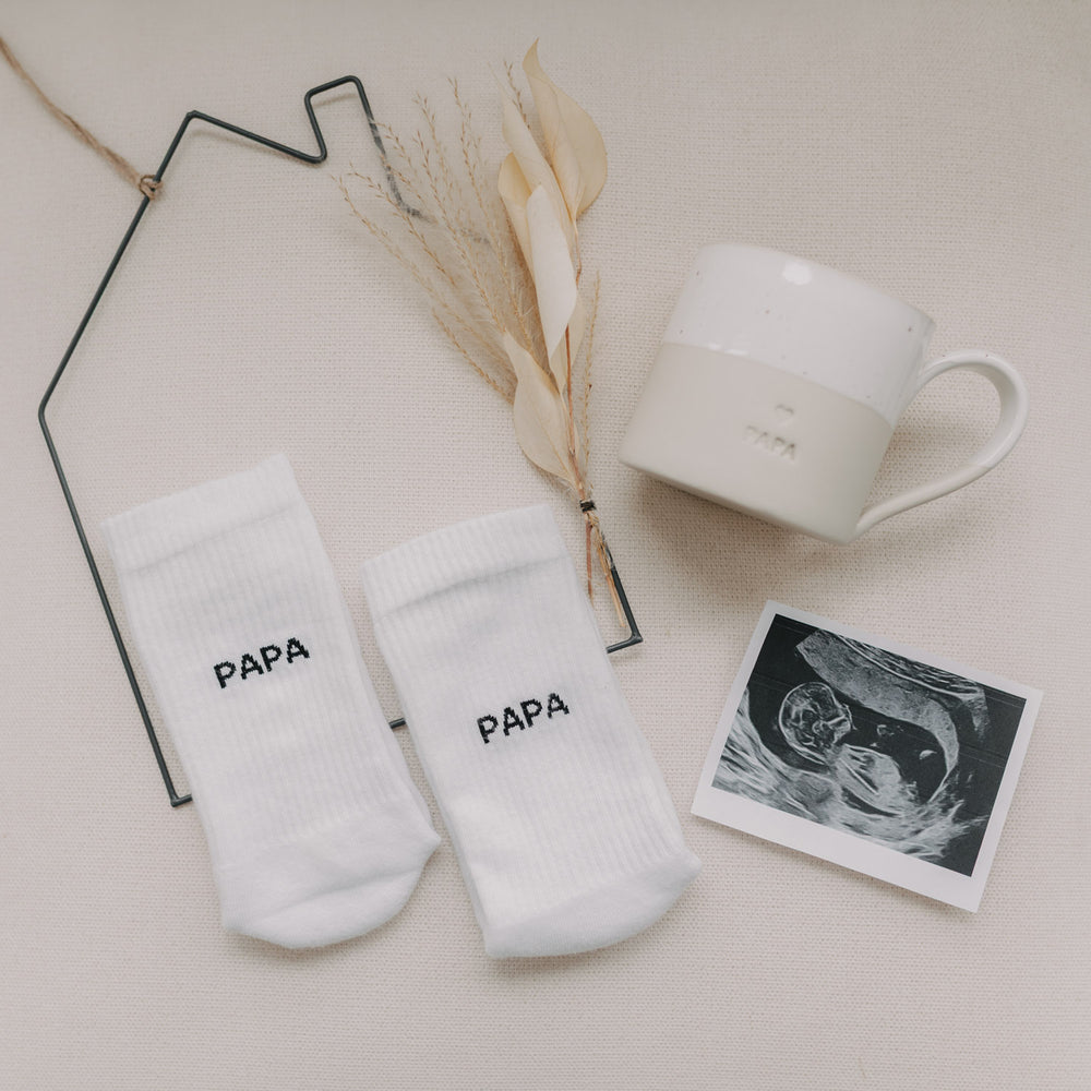 Papa-Socken mit passender Tasse und Baby-Ultraschallbild als Geschenkidee dekoriert.