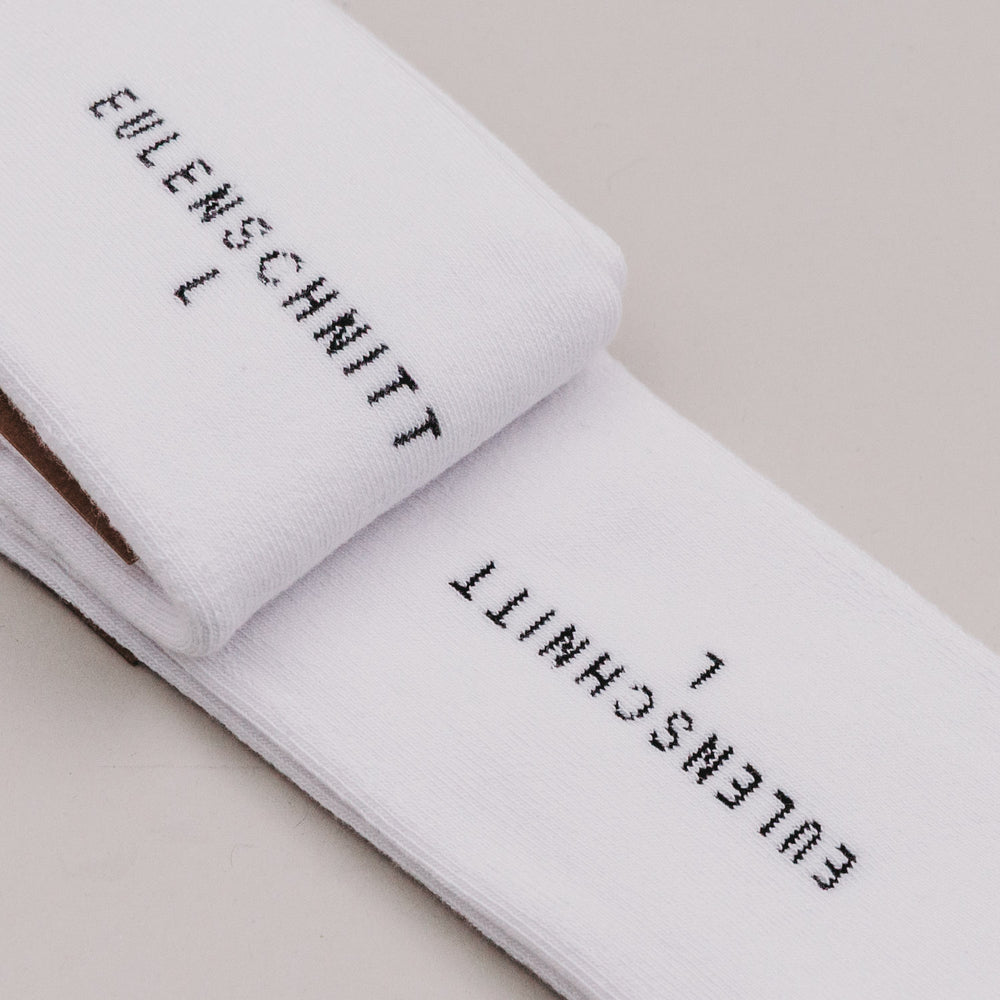 Sohle der weißen Socken mit eingestickter Marke Eulenschnitt und Größenangabe.