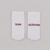 Weiße Socken mit rotem Schriftzug „Team Glühwein“ nebeneinander liegend vor neutralem Hintergrund.