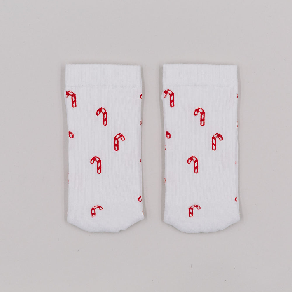 Zuckerstangen-Socken flachliegend auf weißem Hintergrund – weihnachtliches Allover-Muster in Rot.