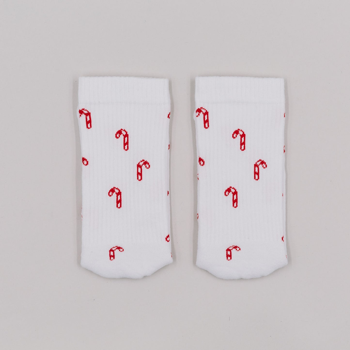 Zuckerstangen-Socken flachliegend auf weißem Hintergrund – weihnachtliches Allover-Muster in Rot.