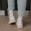 Weiße Herz-Socken von hinten getragen mit hochgekrempelter Jeans und Sneakern