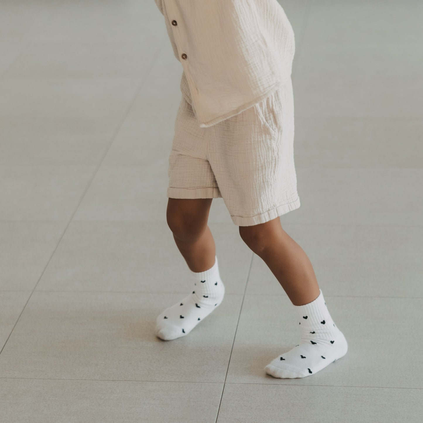 Kind trägt weiße Kids Socken mit schwarzen Herzen von Eulenschnitt