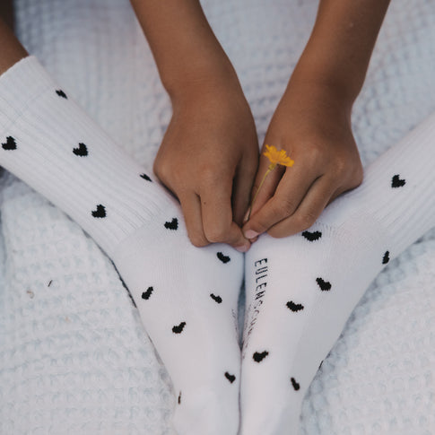 Kind trägt weiße Kids Socken mit schwarzen Herzen von Eulenschnitt