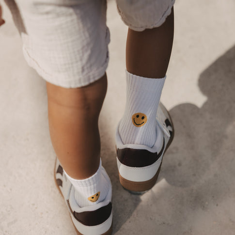 Kind trägt weiße Smiley Socken von Eulenschnitt mit Sneakern
