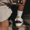 Kind trägt weiße Eulenschnitt Socken mit gelbem Smiley