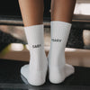 Nahaufnahme der weißen Kindersocken mit den schwarzen Schriftzügen „Easy“ und „Peasy“.