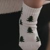 Close-up weiße Baby Socken mit grünen Tannen, gemütliche Winteroptik und weiches Material
