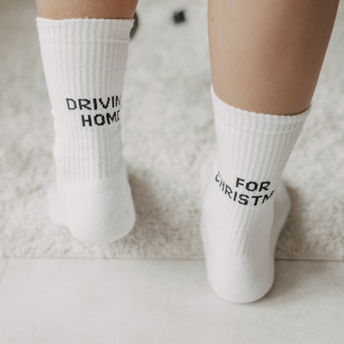 Weiße Weihnachtssocken mit schwarzem Driving Home for Christmas Schriftzug in Nahaufnahme