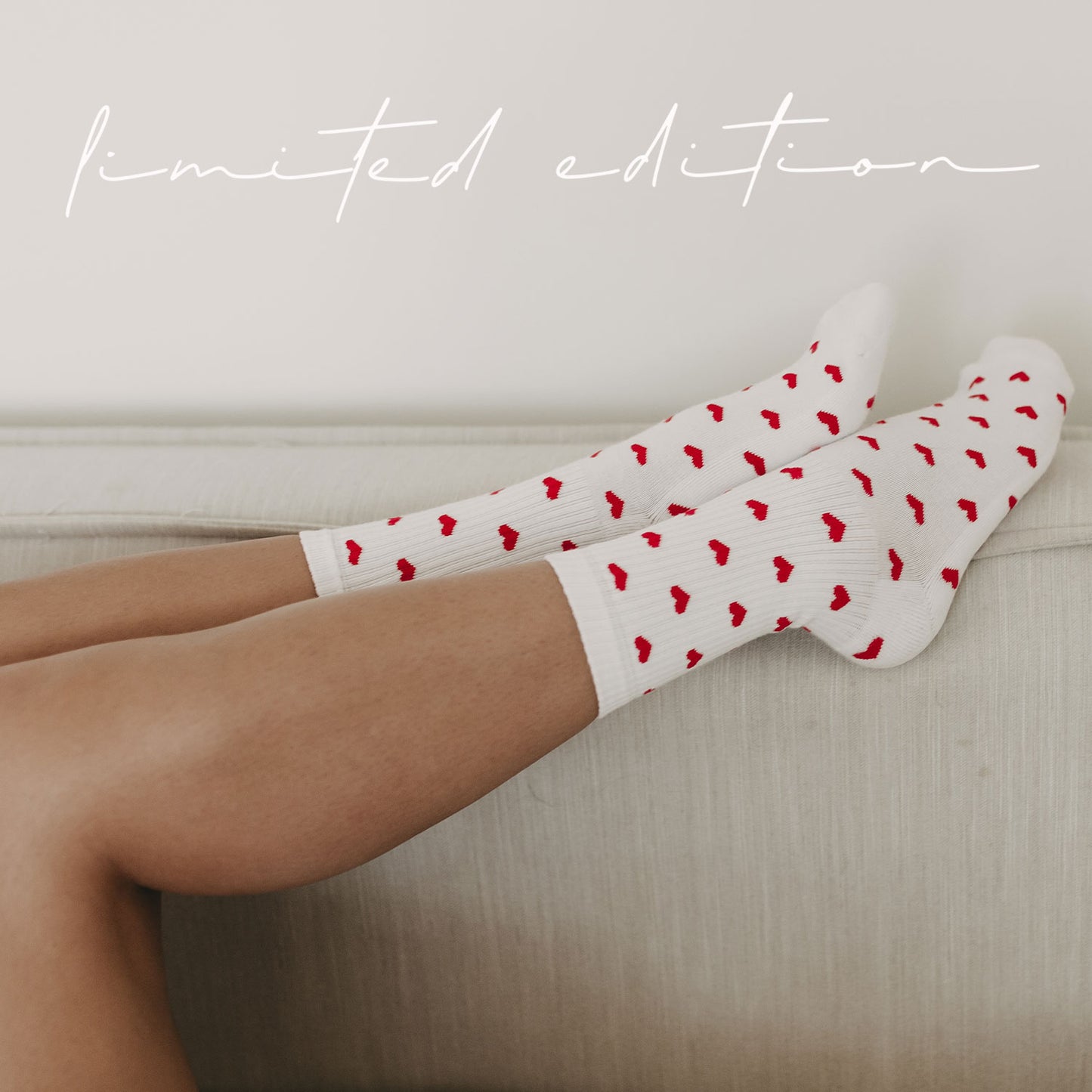 Nahaufnahme: Person liegt entspannt auf einem Sofa und trägt weiße Socken mit roten Herzchen. Schriftzug Limited Edition steht über dem Bild.