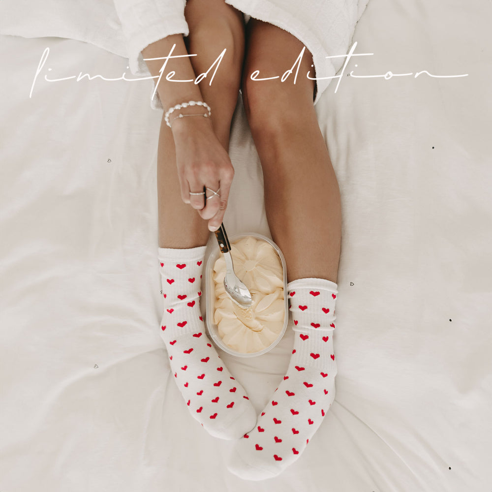 Nahaufnahme: Person sitzt auf einem Bett mit einer Schale Vanilleeis zwischen den Füßen, trägt weiße Socken mit roten Herzchen. Über dem Bild der handgeschriebene Schriftzug Limited Edition.