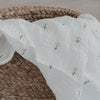 Musselintuch mit Gänse- und Blumenprint über geflochtenem Korb drapiert