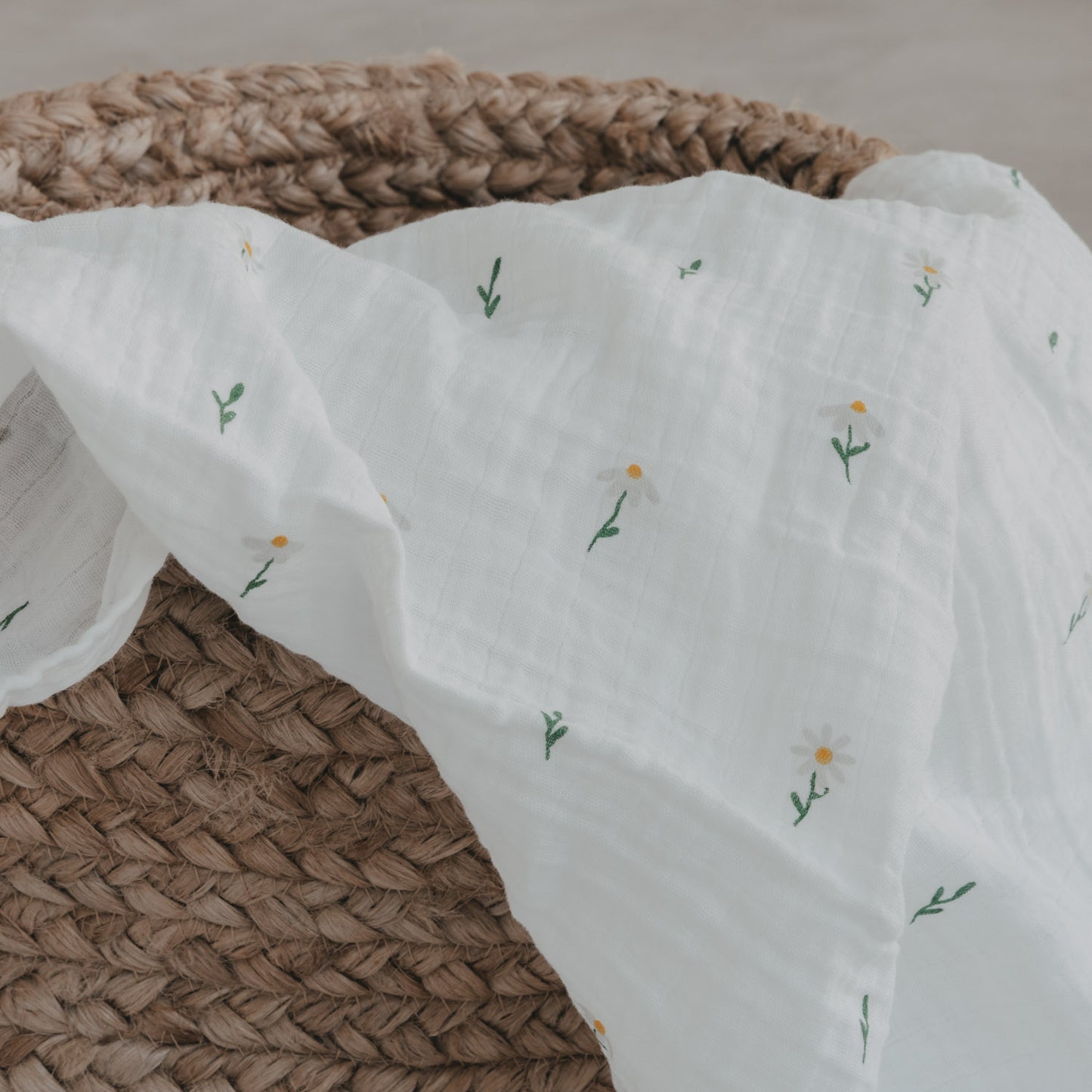 Musselintuch mit Gänse- und Blumenprint über geflochtenem Korb drapiert