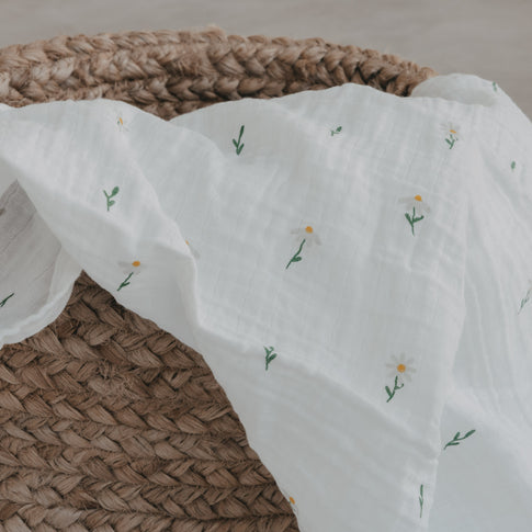 Musselintuch mit Gänse- und Blumenprint über geflochtenem Korb drapiert
