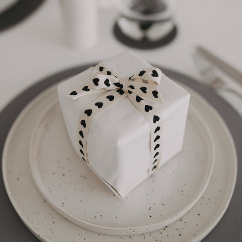Geschenk mit Herz-Geschenkband als Tischdekoration gedeckt.