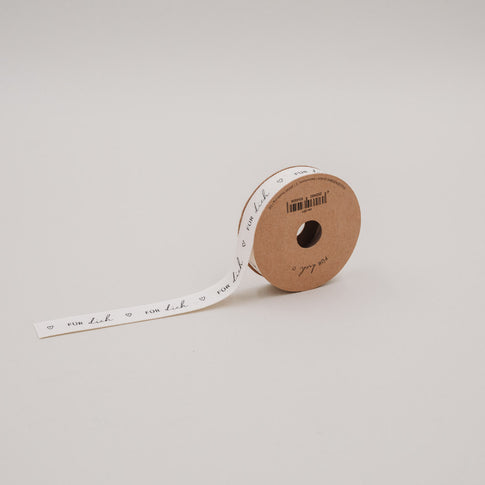Teilabgerollte Geschenkband-Rolle „Für dich“ aus Baumwolle auf schlichtem, hellem Hintergrund.