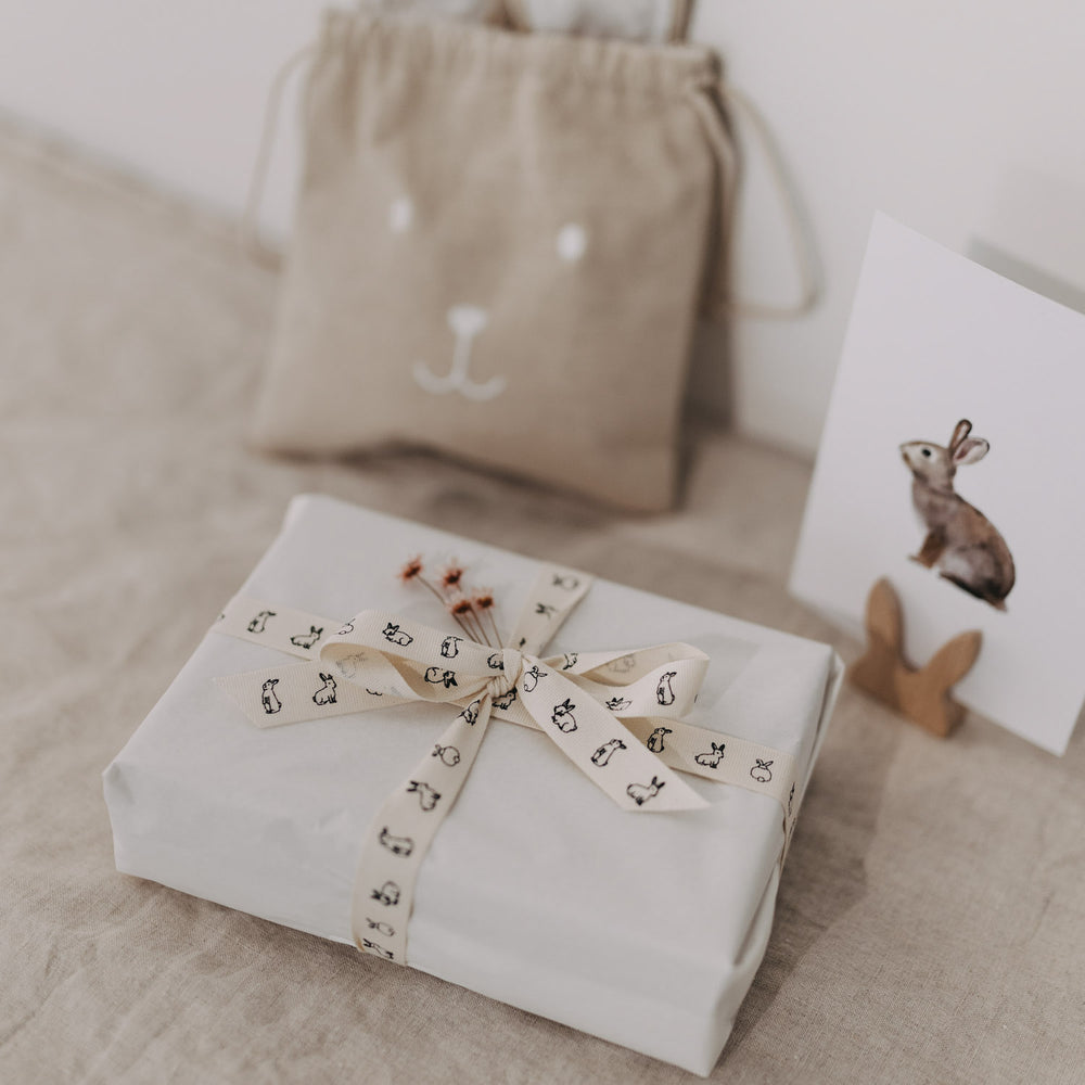 Eingepacktes Geschenk mit Kaninchen-Geschenkband vor Beutel und Hasenkarte.