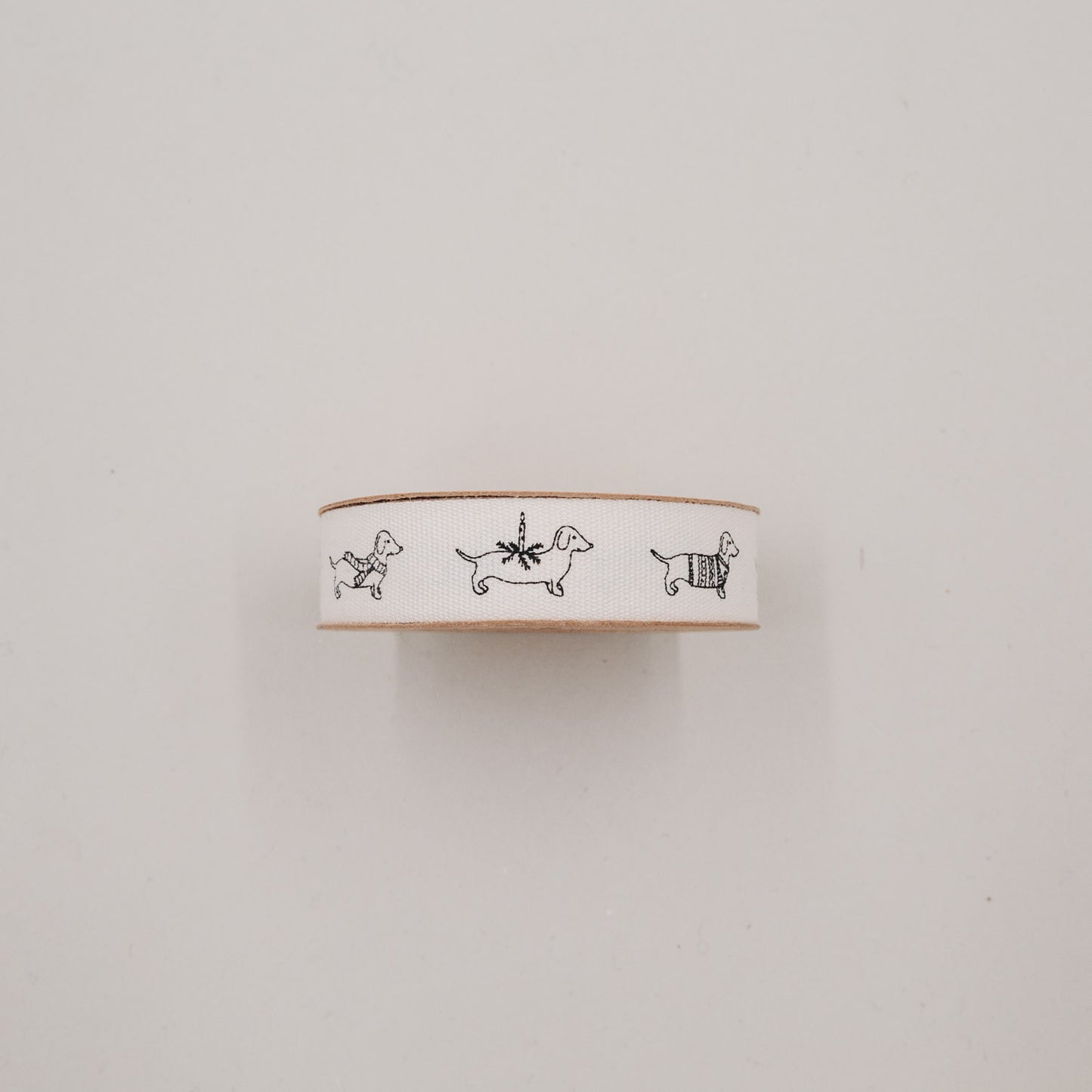 Detailansicht Baumwollband mit Dackeln in Pullover, Schal und Geschenkpaket auf weißem Hintergrund