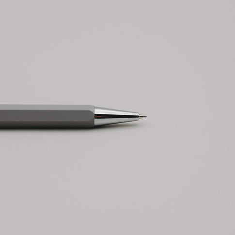 Grauer Druckbleistift mit silberner Spitze auf hellem Hintergrund, minimalistisch und elegant.