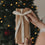 Weihnachtsgeschenk mit Eulenschnitt Geschenkband Ho Ho Ho vor beleuchtetem Weihnachtsbaum