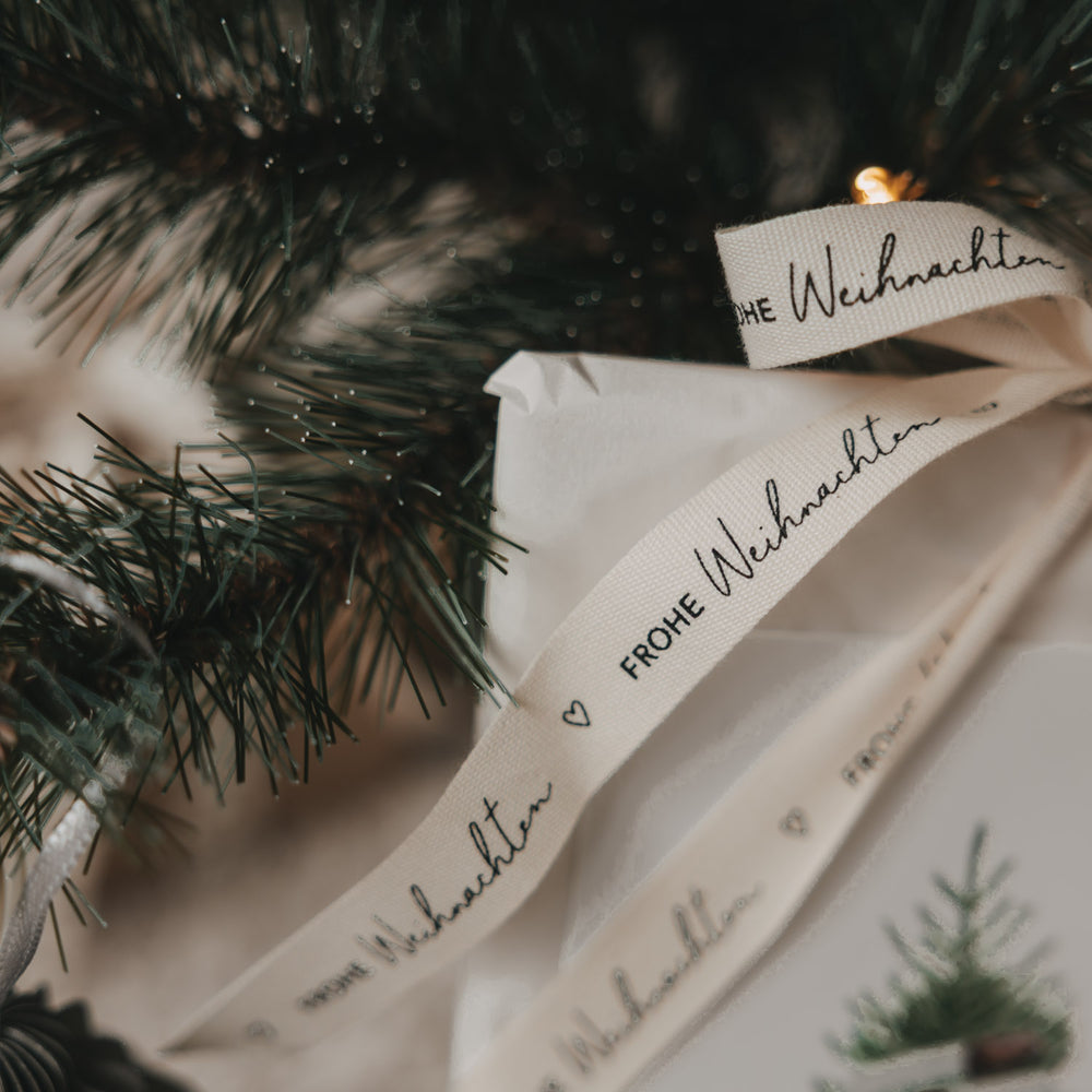 Beiges Eulenschnitt Geschenkband Frohe Weihnachten mit schwarzem Schriftzug und Herzmotiv in Nahaufnahme
