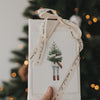 Weihnachtsgeschenk mit Eulenschnitt Geschenkband Frohe Weihnachten vor beleuchtetem Weihnachtsbaum