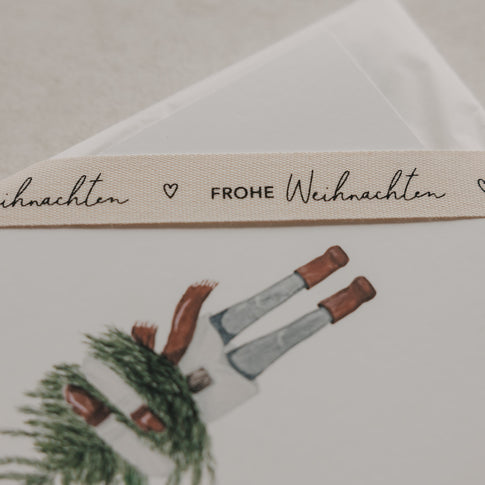 Beiges Geschenkband Frohe Weihnachten von Eulenschnitt mit schwarzem Schriftzug und kleinem Herz