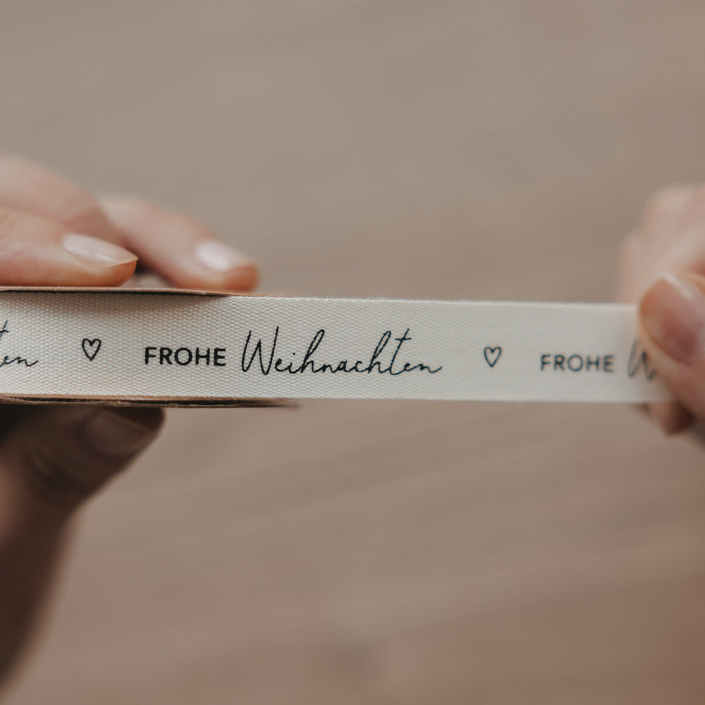 Beiges Eulenschnitt Geschenkband Frohe Weihnachten auf Rolle mit schwarzem Schriftzug und Herz