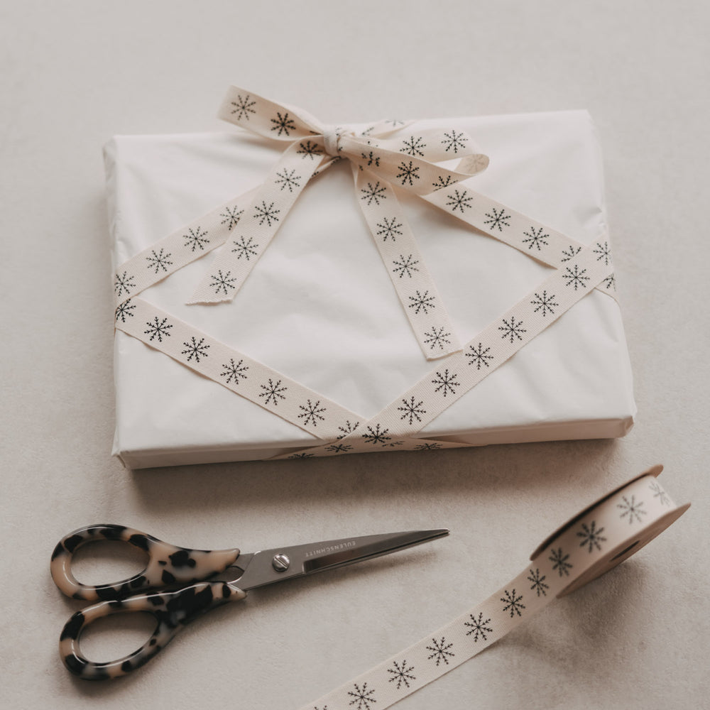 Weißes Weihnachtsgeschenk mit beigem Eulenschnitt Geschenkband und schwarzen Schneeflocken