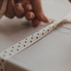 Beiges Geschenkband mit schwarzen Herzen beim Verpacken eines Geschenks