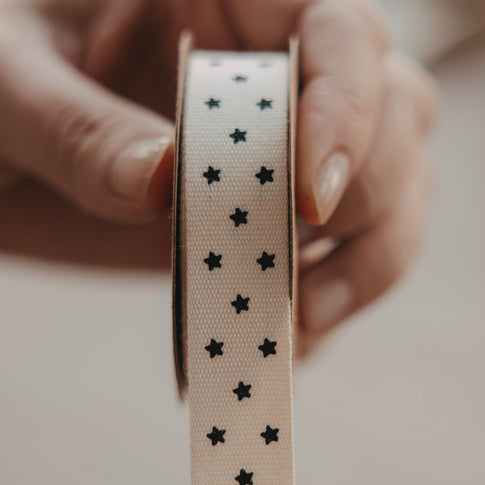 Detailansicht des beigen Geschenkbands mit schwarzen Sternen auf einer Rolle